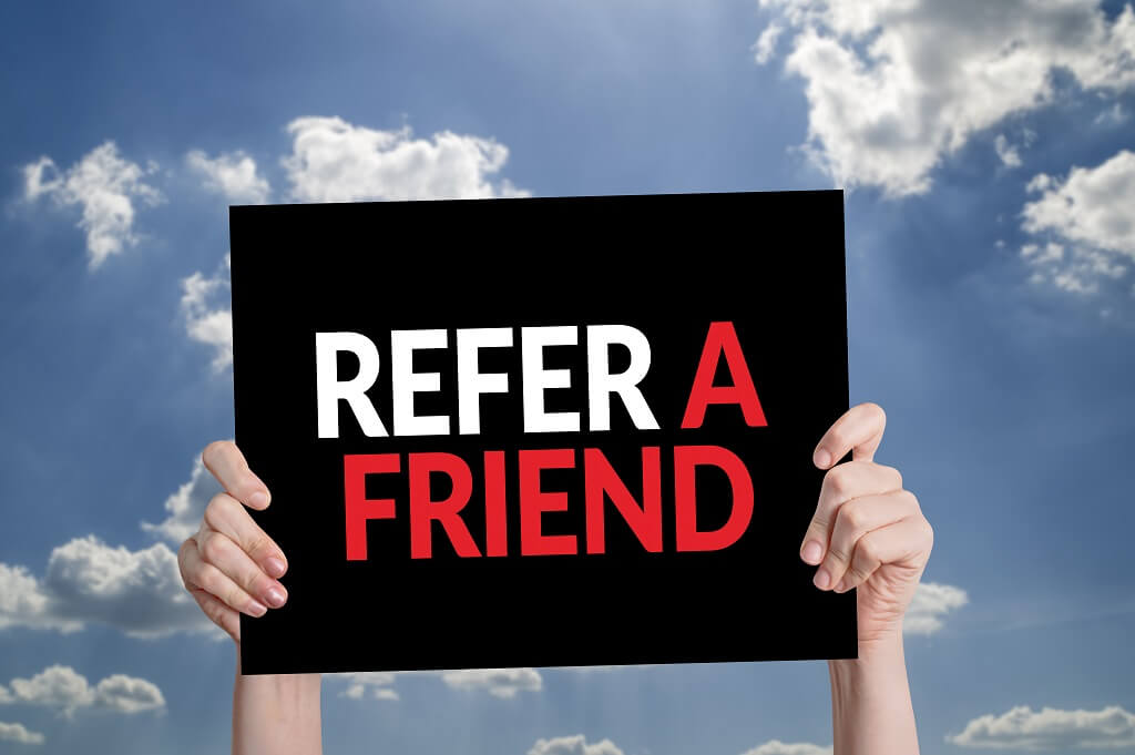 sky and cloud background behind hands holding sign that says refer a friend