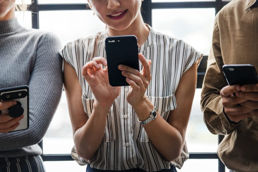 Woman holding phone next to coworkers