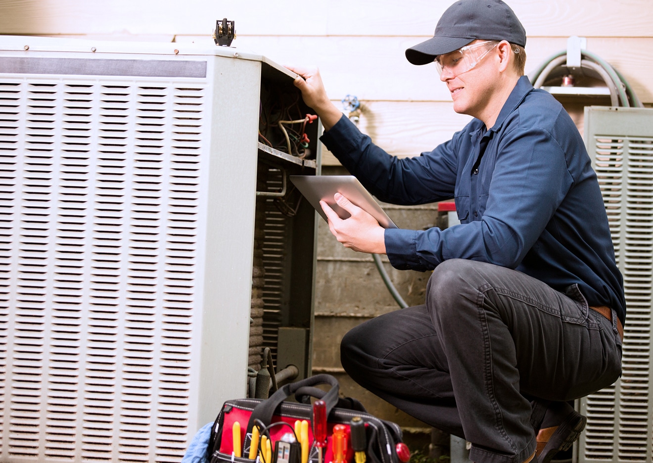 hvac tech holding tablet working on unit