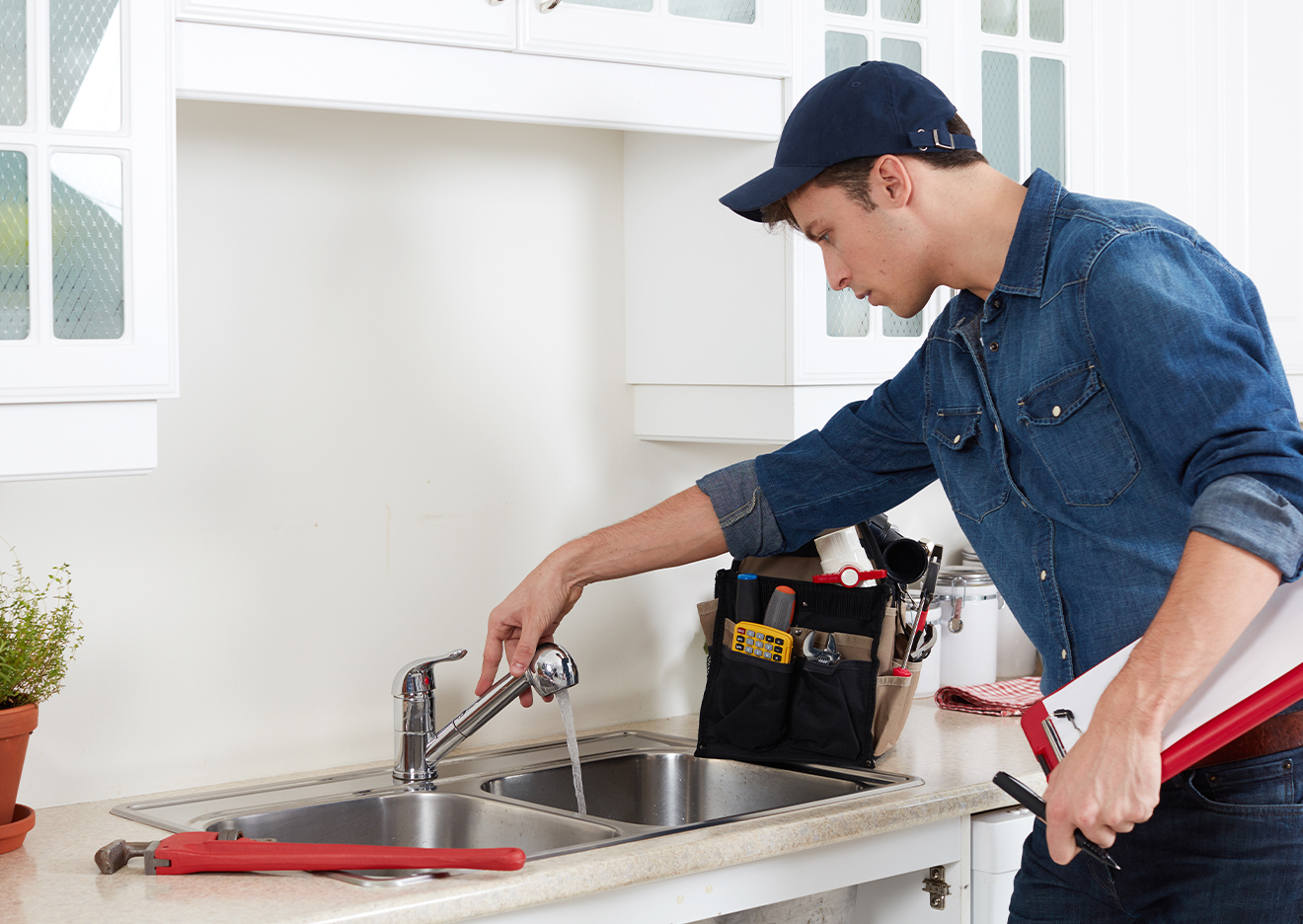 young male plumber working on a kitchen sink